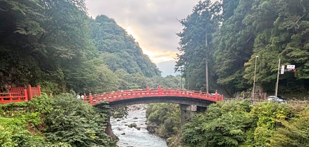Puente Shinkyo en Nikko, Japón, un icónico puente rojo sobre el río Daiya, rodeado de naturaleza exuberante.